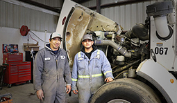 Mentor and student standing in front of a truck with the engine compartment open